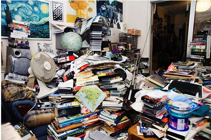 Stacked books and household items in an Auburn Hills hoarding cleanup area